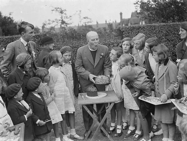 Canon Rs Greaves shows of a cake to children in Chislehurst, Kent