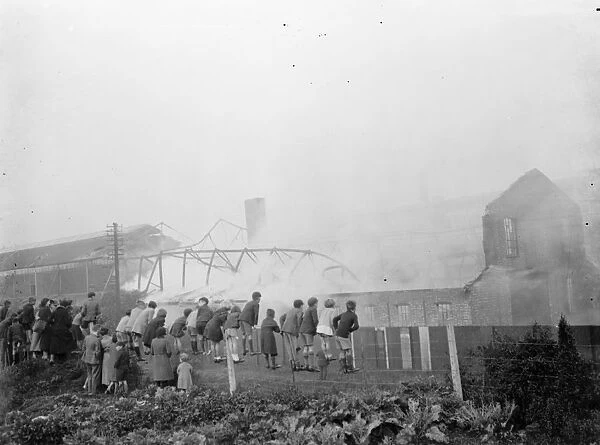 Children climb on a fence to watch the fire at the Vickers factory in Crayford, Kent