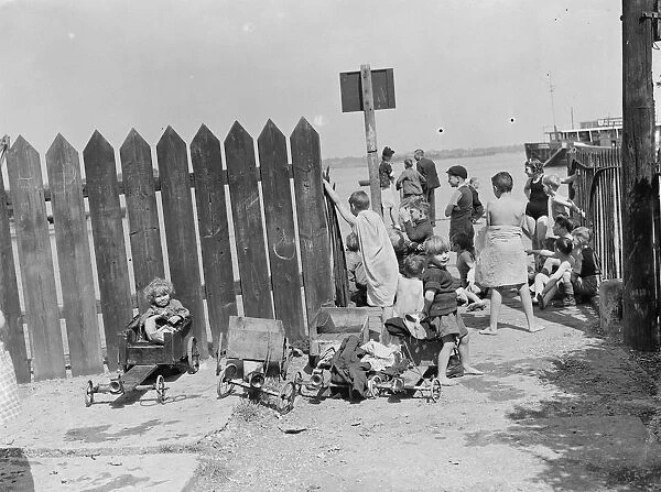 Children have come to the riverside on the Thames estuary at Gravesend, Kent, to