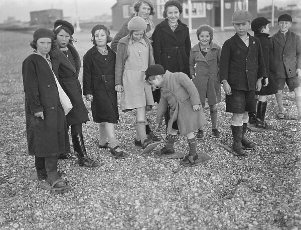Children playing on the shingle beach at Dungeness. They use beach shoes to walk