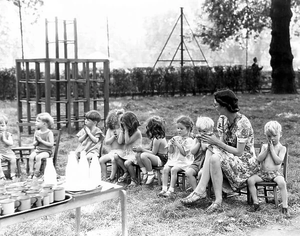 The children from St Leonards Day Nursery sit in a line with their nursery teacher
