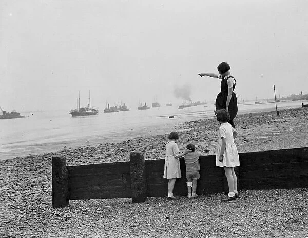 Children stand on the sea defences at Gravesend river front and look out over the