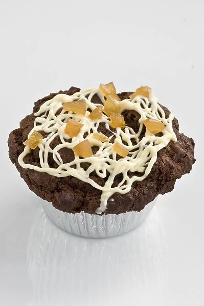 Chocolate muffin decorated with drizzled icing with dried mango pieces credit
