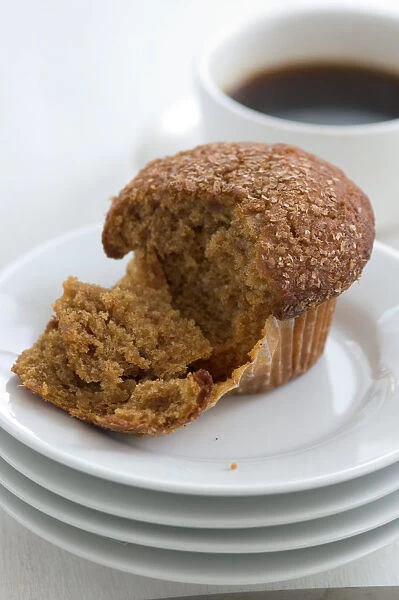 Cinnamon bran muffin on stack of white plates with cup of black coffee credit