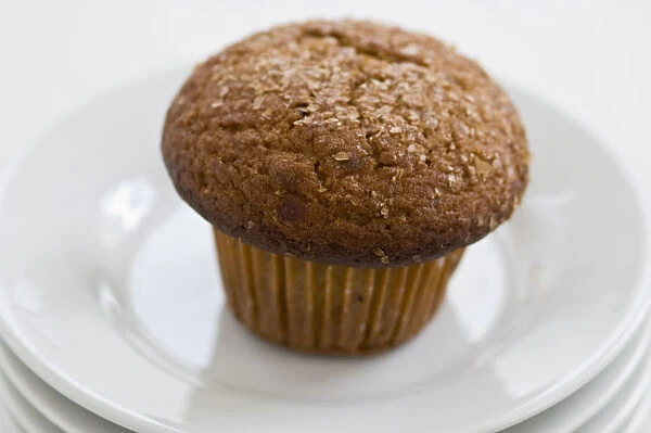 Cinnamon bran muffin on stack of white plates with cup of black coffee credit