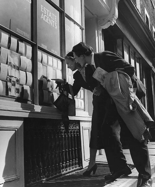 Couple lookng at houses in the window of an estate agent - 1950 ?TopFoto