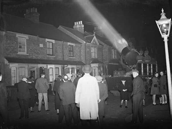 A crowd watching the mobile Army searchlight as it progresses down their street