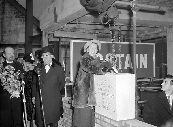 Dame Flora Robson with a trowel in her hand is laying the foundation stone of the