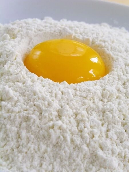 A whole egg yolk broken into a pile of sifted flour credit: Marie-Louise Avery