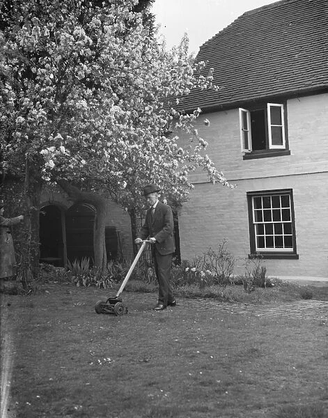 An elderly man cuts the grass at his cottage garden in Farningham, Kent. 7 April 1938