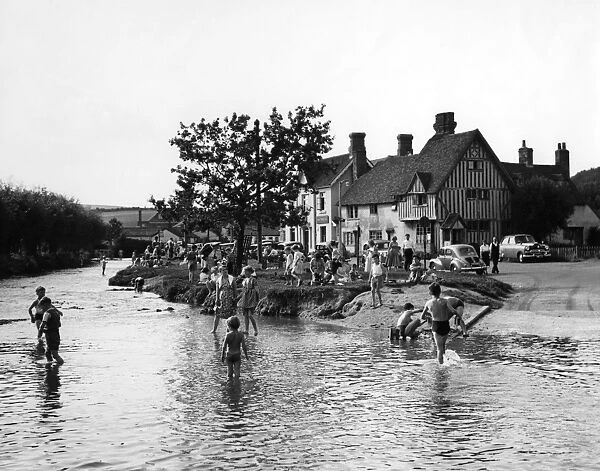 Families play in the flood water in Eynsford, Kent. Some of the children paddle others