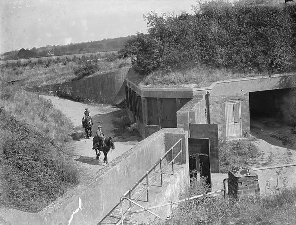 Farm workers ride work horses past old fort buildings on their farm at Farningham, Kent