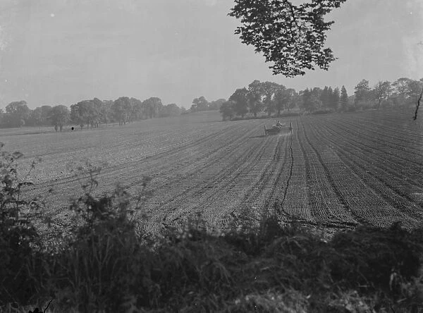 A farmer fertilising a fields with his tractor. 1939