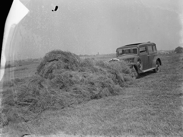 A farmer haymaking using a car. The car has an attachment to the front allowing