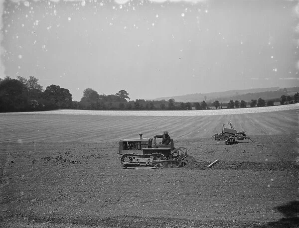 A farmer and his tank track tractor, harrow a field 1936