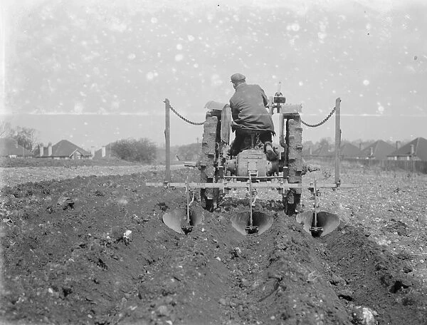 A farmer and his tractor plough a field. 1935