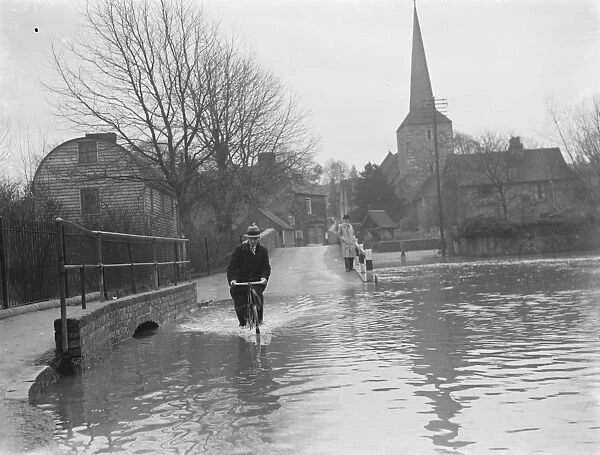 Flooding in Eynsford, Kent. Cyclist rides through the water. 1937