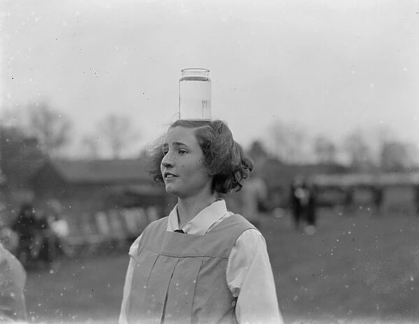 Girl balances a jar of water on her head. 1935