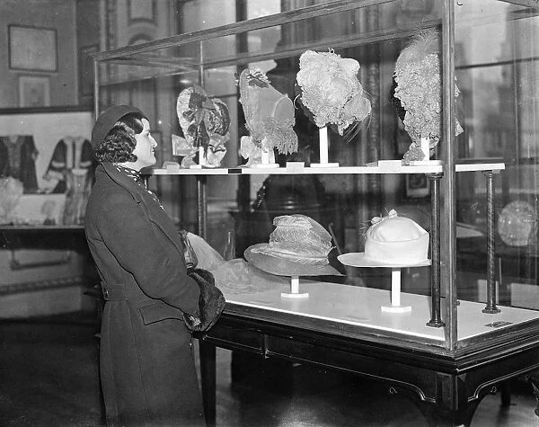Girl in modern beret examines headgear of bygone days. 5 February 1935