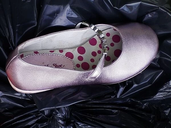 Girls pink party shoe discarded on top of a black bin liner