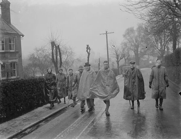 A group of young hikers stroll through the rain. 1937