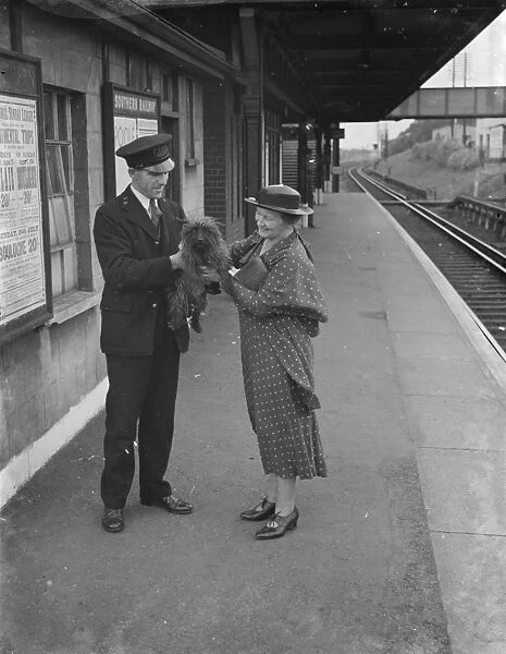 One happy dog is held aloft by a train station attendant with Mrs Boune Williams