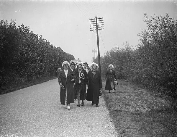 Hop pickers walk along a country lane. 1935