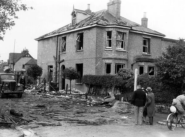 A house showing considerable damage, surrounded by debris after a near miss