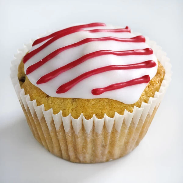 Iced cupcake with red stripes on white icing credit: Marie-Louise Avery  /  thePictureKitchen
