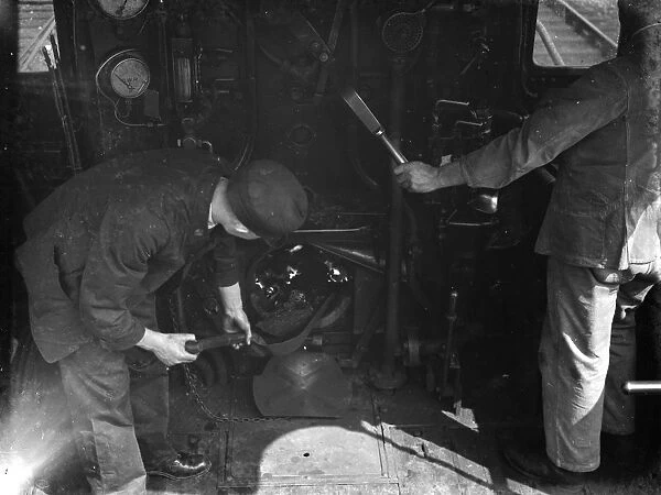 Inside a railway engine cabin. The fireman shovels coal into the fire. 1938
