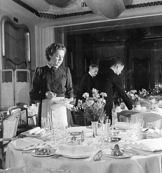 Irene Heckman, a waitress at the Lyons Trocadero, lays extra table settings on the