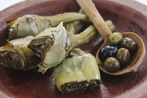 Italian grilled and marinated artichokes on brown dish credit: Marie-Louise Avery