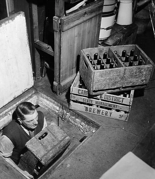 Joe, the landlord, brings up bottles of beer from the cellar to sell at the Globe Tavern