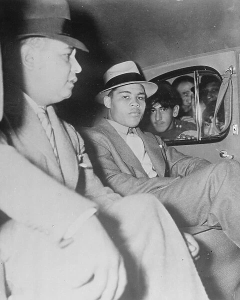 Joe Louis seated calmly in his car as admirers press their faces eagerly to the windows
