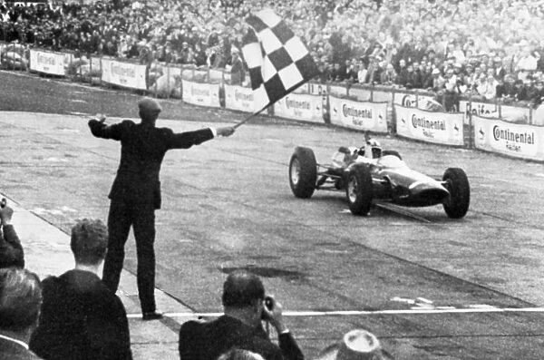 John Surtees roars across the finish line in his Ferrari to win the German Grand Prix at Adenau