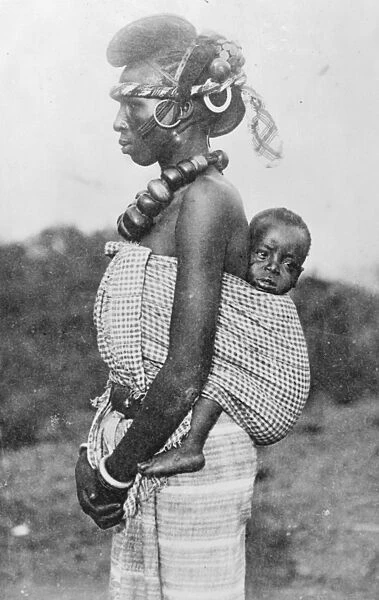 A lady of smart society in French Guinea with her baby on her back. She belongs