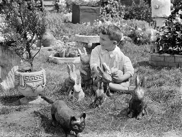 A little boy with some of the clay rabbits made by Mr Sadler. 1938