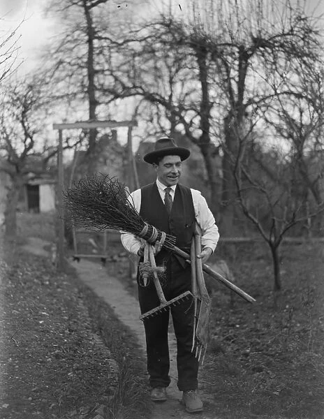 Man carrying garden tools, rake, spade and besom broom. 1935