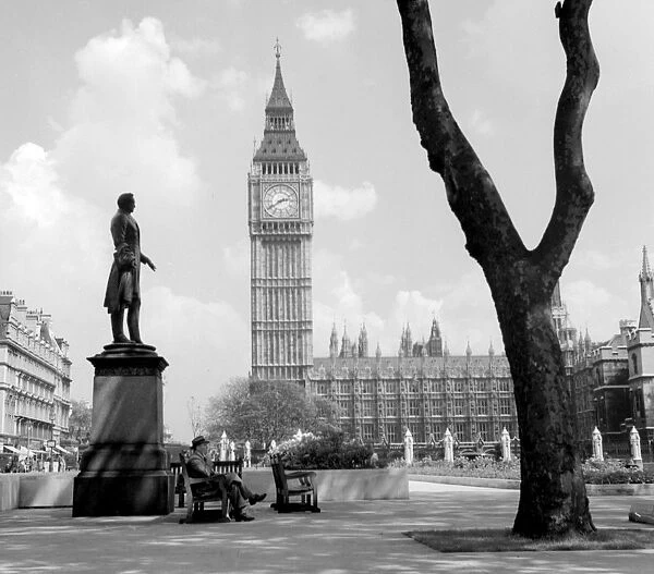 A man relaxes by the statue of Viscount Palmerston in Parliament Square with Big Ben