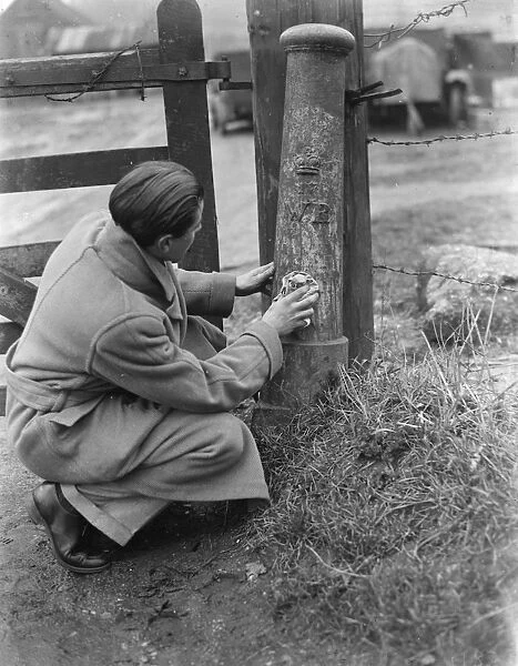 A man uses a cloth to try and clean a boundary post. 1937