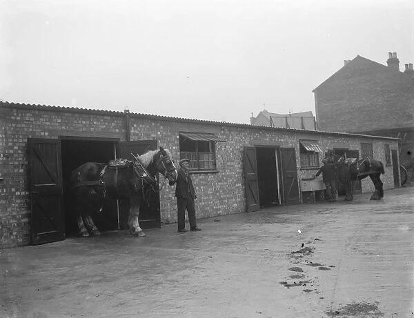 A man walks a horse out of the stables. 1936