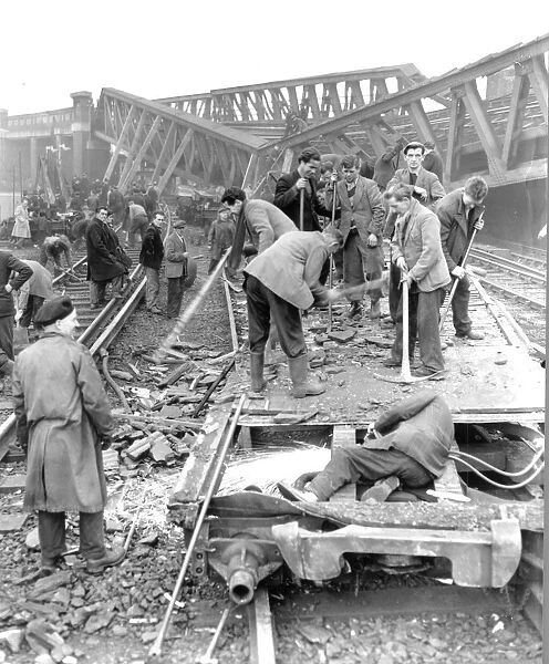 A man works with an acetylene cutting the remains of a train carriage in the foreground