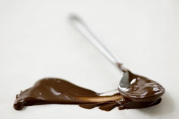 Melted chocolate on teaspoon, with smear of chocolate on greaseproof paper credit