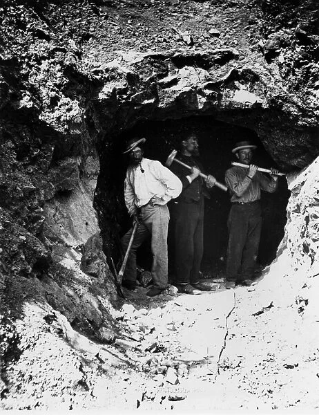 Three men standing in a tunnel, these men have just begun to bore one of three tunnels