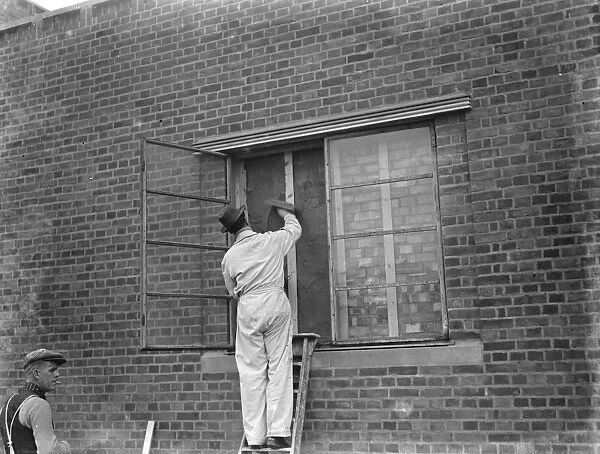 A modern police station on Wellhall Road, Eltham, London. A worker is plastering over a window