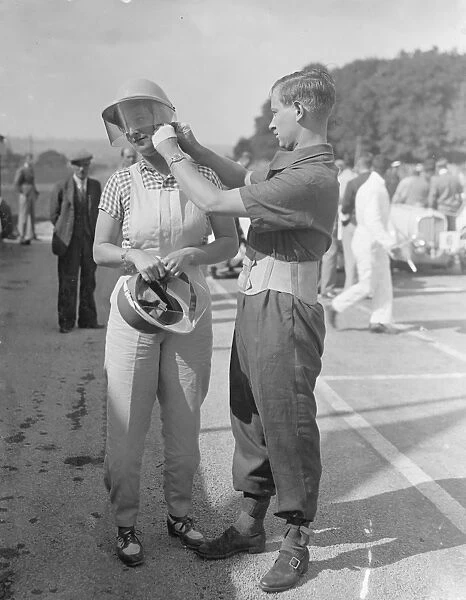 Mr A. C Dobson adjusting his wifes helmet before she took the track in her Fiat