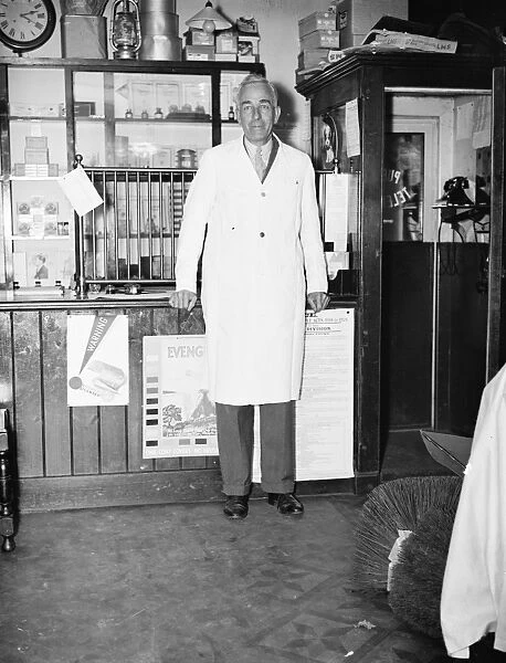 Mr George May, Postmaster of Downe, Kent by his Post Office counter and telephone