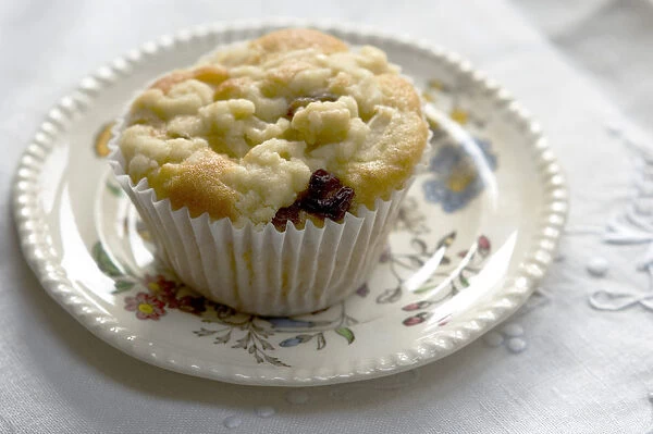 Muffin baked with topping of fresh grated apple on small patterned plate credit