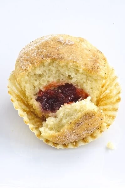 Muffin with sugary top filled with jam (jelly), broken open to show filling. A muffin