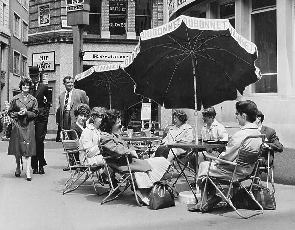 Office girls take their lunch break al fresco in a continental style table and umbrella